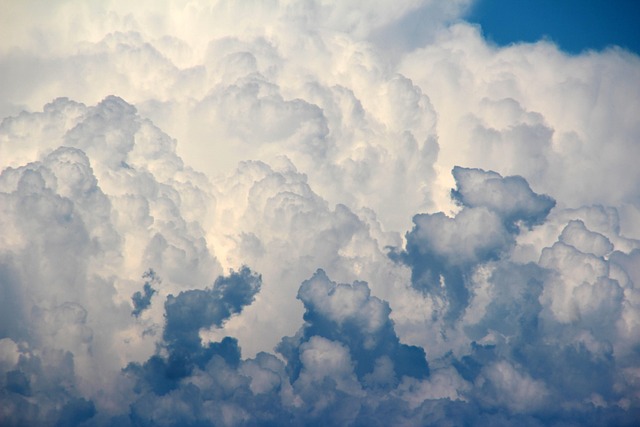 Białe kłębiaste chmury cumulus na tle błękitnego letniego nieba nad polem